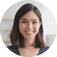 Person with shoulder-length hair smiling at the camera, wearing a dark shirt with white polka dots, reminiscent of a delicate fabric pattern.