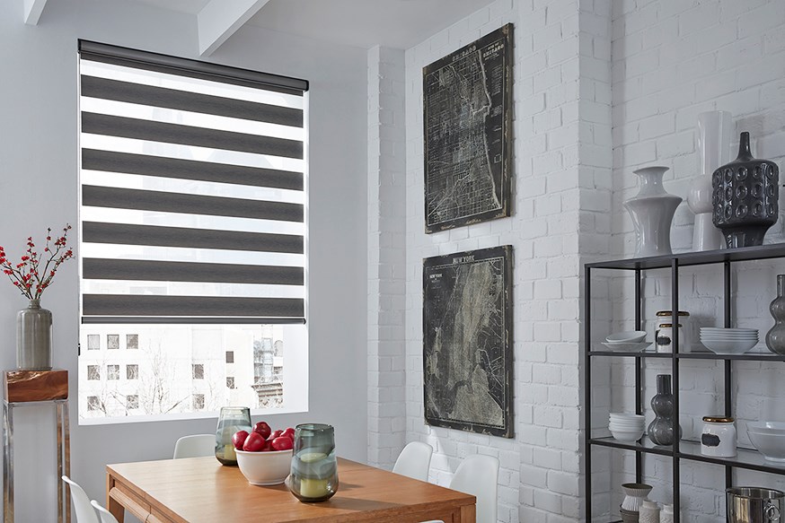 Dining area with a wooden table, white chairs, Zebra Blind Range B, and decorative items on shelves and walls set against white brick walls.