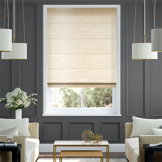 A modern living room with gray paneled walls, a large window adorned with beige fabric Roman blinds, two white sofas, and a sleek white coffee table enhanced by gold geometric decor pieces. White pendant lights elegantly hang from the ceiling.