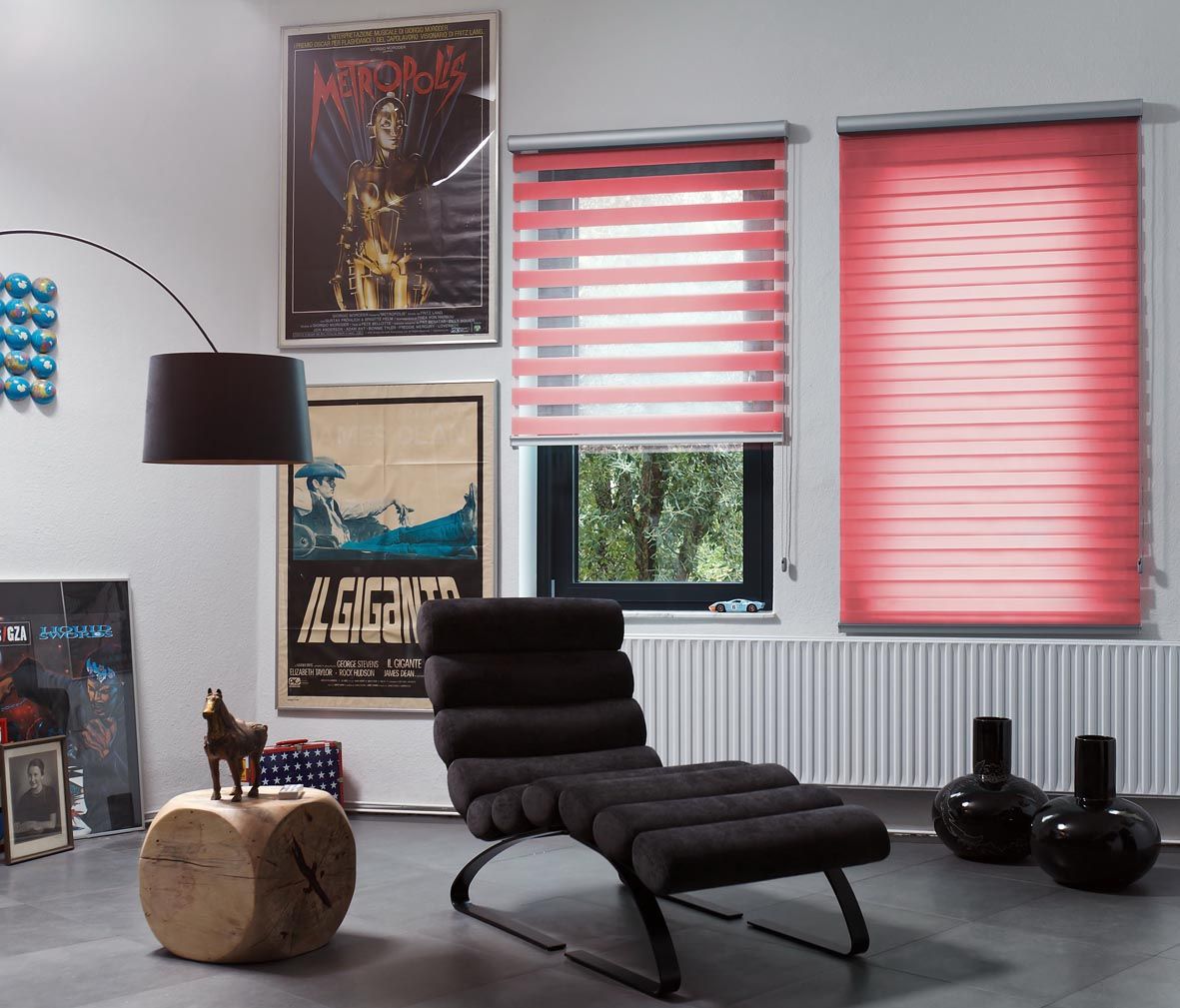 Modern room with a black lounge chair, spherical wooden side table, and two posters. Two windows feature Zebra Blind Range B for a pop of color, while decor adorns the floor and walls.