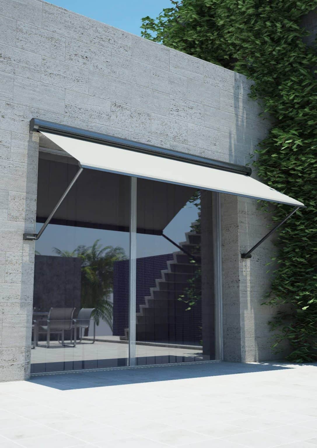 A white retractable awning covers a glass sliding door on a modern gray stone building with greenery climbing the wall.