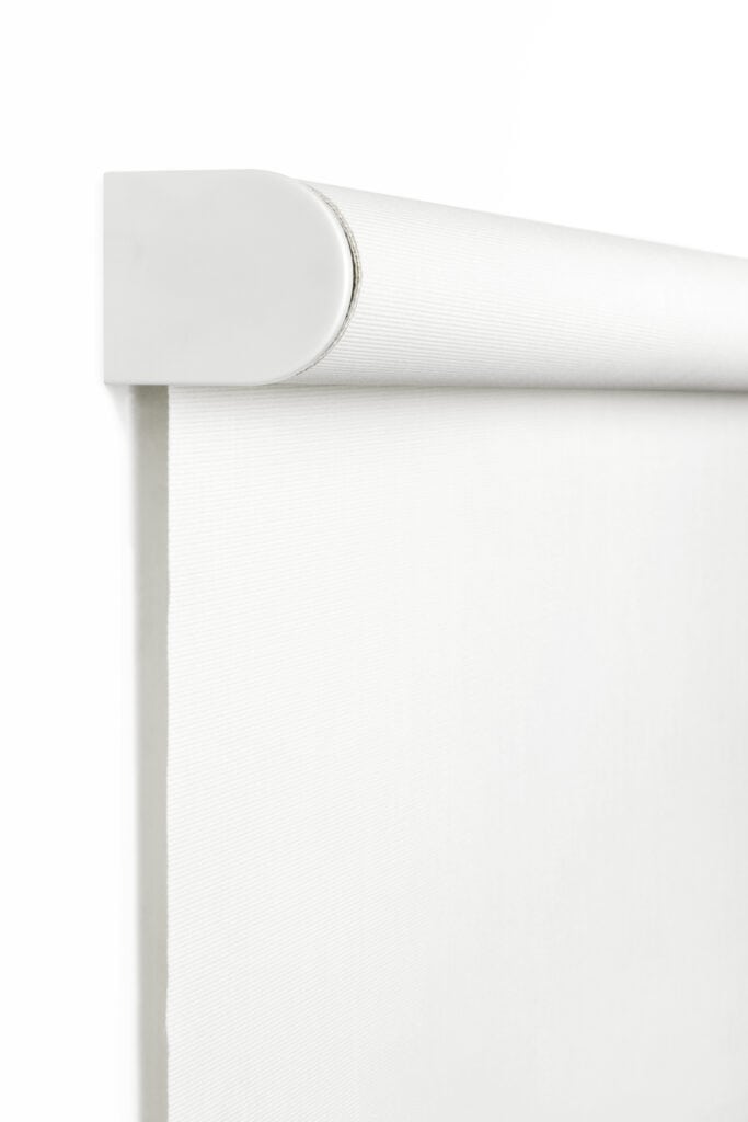 Close-up of a white roller blind partially unrolled with a rounded metal housing.