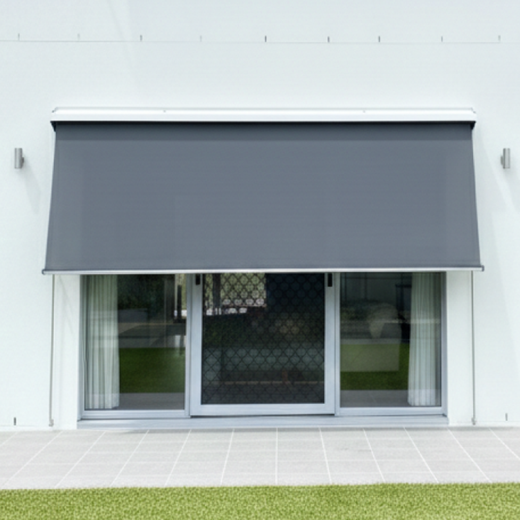 A modern grey retractable awning extends over sliding glass doors with white curtains and Pivot Arm Blinds, overlooking a tiled patio and green lawn.