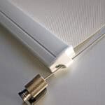 Close-up of Outdoor Wired Guide Blinds in white, highlighting the textured surface, end cap, and attached metallic tension cable.