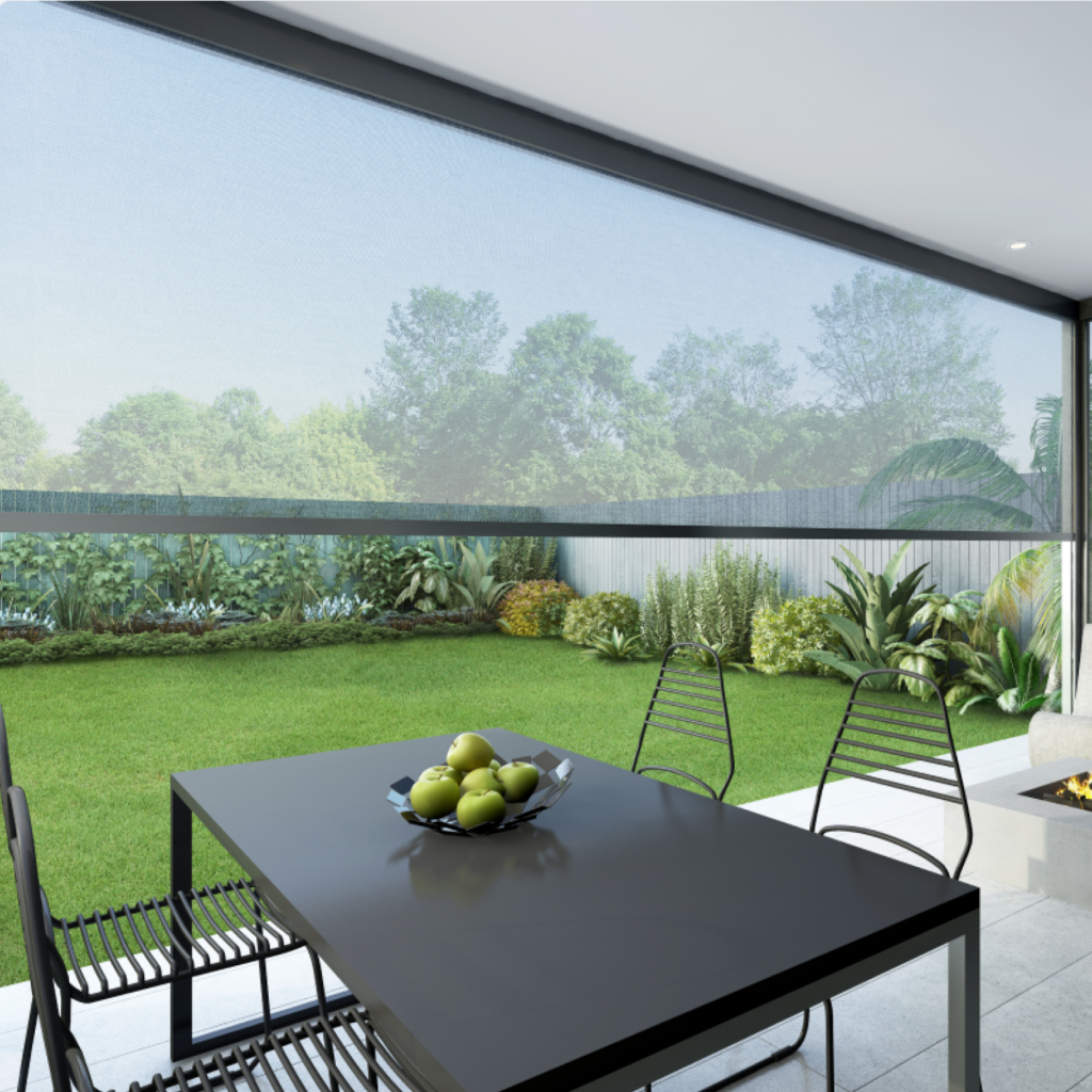 A patio dining table with chairs faces a garden, seen through Zipscreen Blinds that softly filter the light. A bowl of green apples rests on the table.