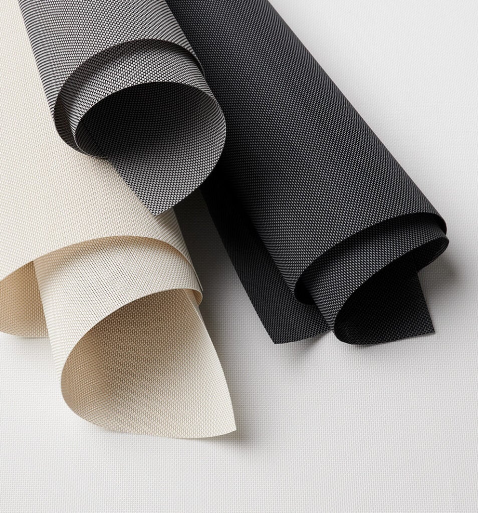 Three textured fabric rolls, two in beige and one in black, are arranged on a flat, light-colored surface.