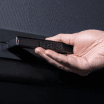 A hand holds a black bar labeled “ZIPSCREEN” against a dark background.