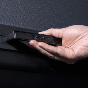 A hand holds a black bar labeled “ZIPSCREEN” against a dark background.