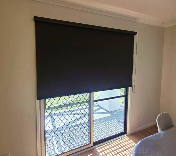 A dark roller blind covering the top half of a sliding glass door.
